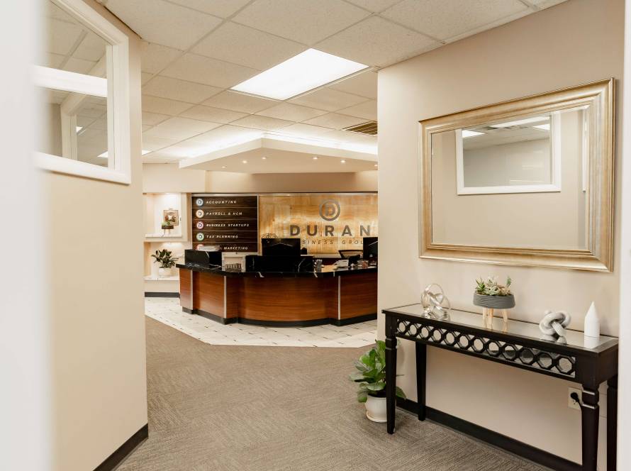 View from a hallway looking into the Duran Business Group office reception desk with service signs on the wall.